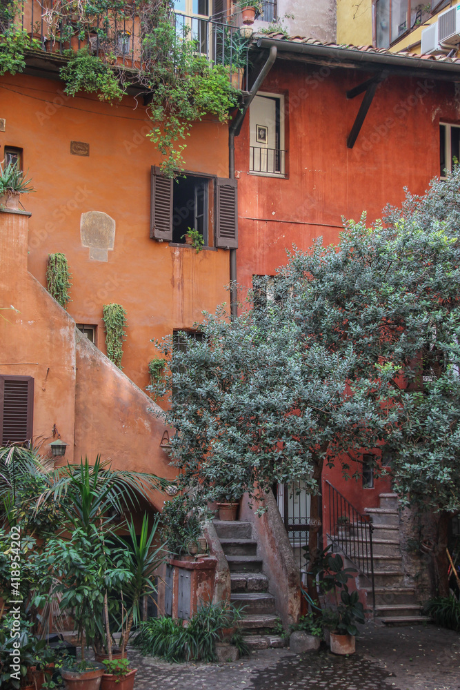 Fototapeta premium kolorowe stare kamienice z wejściem po schodach wśród zielonych drzew z drewnianymi oknami i żaluzjami