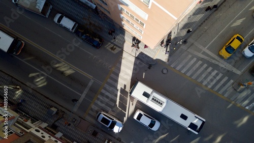 Aerial view of crosswalk and intersection road at the city center. The sunlight is coming through the buildings. people cross the pedestrian path also.