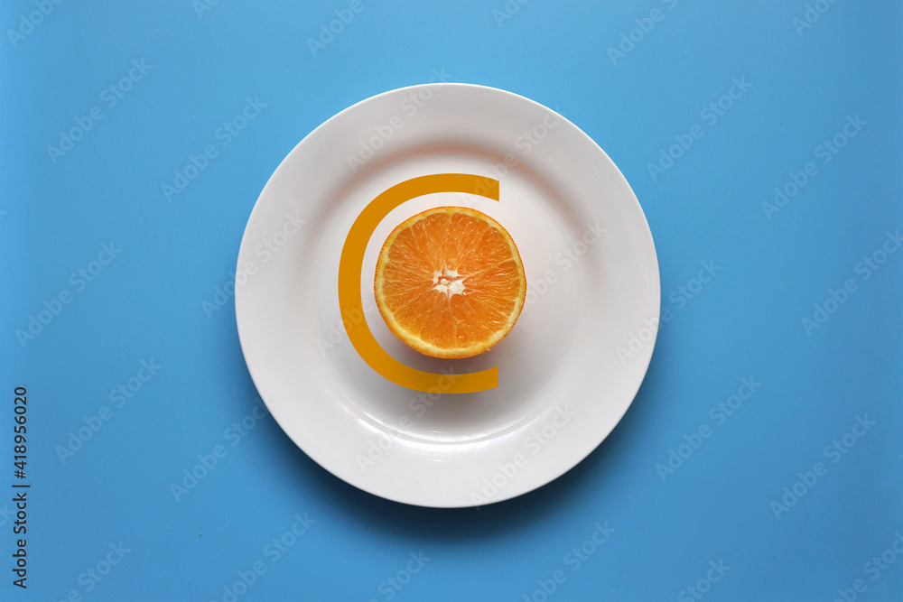 An orange on a white plate and the inscription vitamin C. Getting vitamins from food and proper nutrition An orange on a white plate and the inscription vitamin C. Getting vitamins from food and proper nutrition