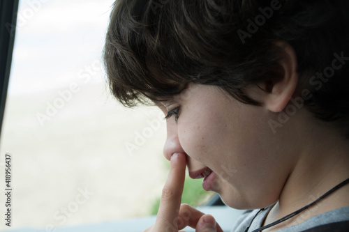 The boy uses his fingers to poke into his mouth photo