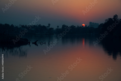 A beautiful sunset at Rabindra Sarobar Lake in Kolkata  with reflection of golden looking sun in lake water.