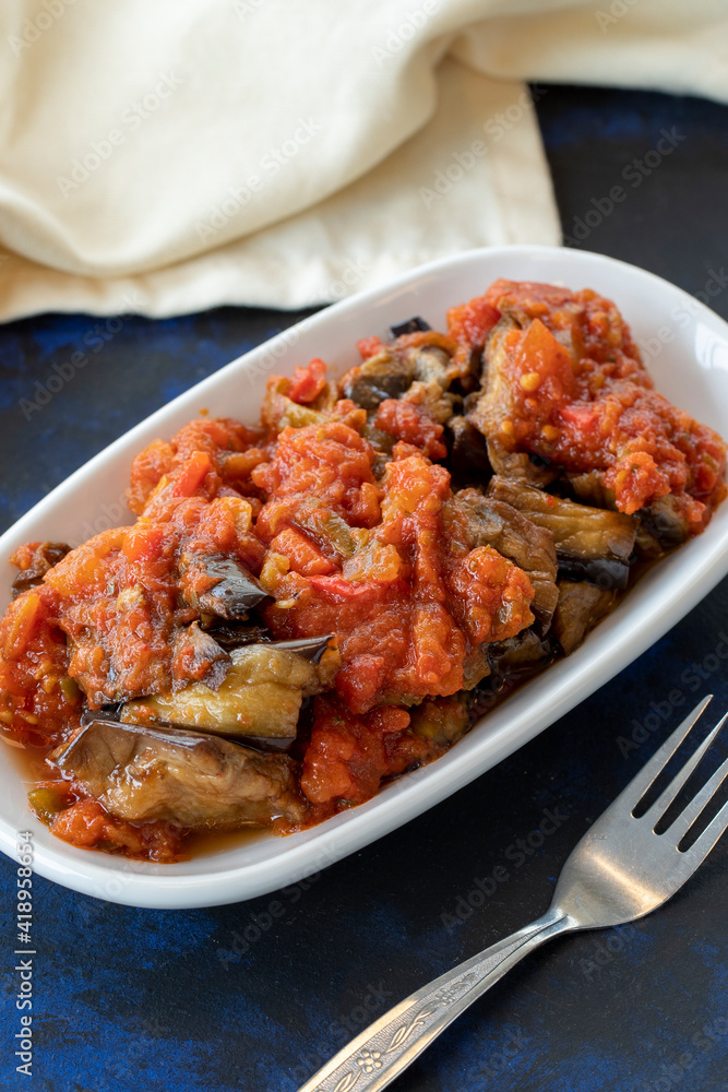 Grilled eggplant salad appetizer with tomato sauce (with eggplant sauce or saksuka). Traditional Middle Eastern meze beside the main course. Layout on dark wood Grilled eggplant salad appetizer with tomato sauce (with eggplant sauce or saksuka). Traditional Middle Eastern meze beside the main course. Layout on dark wood