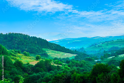 mountain slopes covered with green forest blue sky. Landscape of mountains.