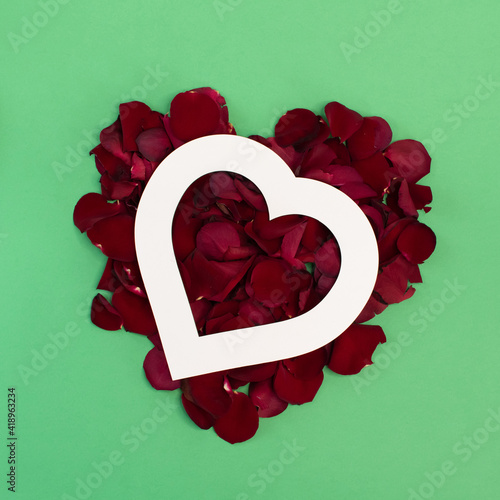 heart on rose petals, scarlet rose on green background, creative concept for March 8 and love