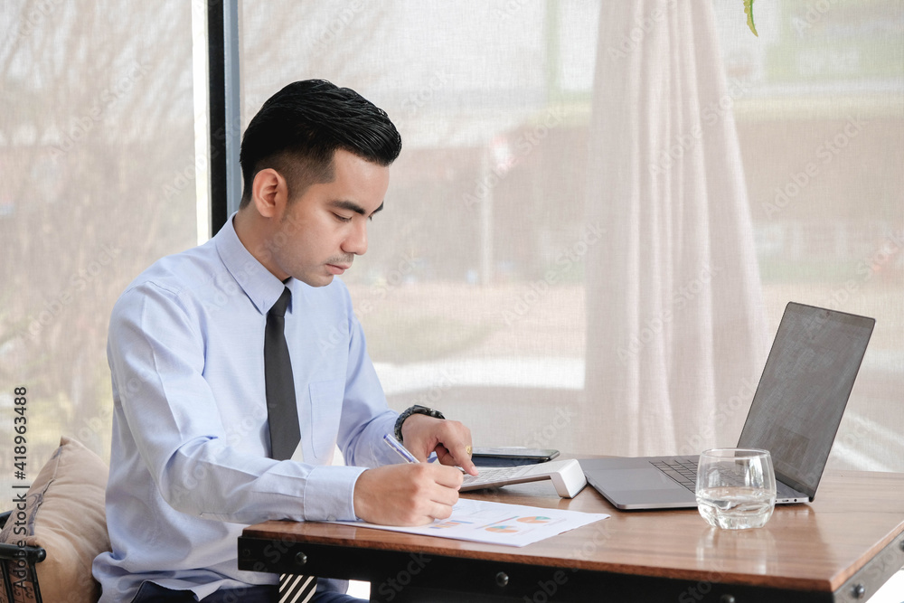 Young asian business man working with laptop, tablet and papers on desk at office. Young asian business man working with laptop, tablet and papers on desk at office.