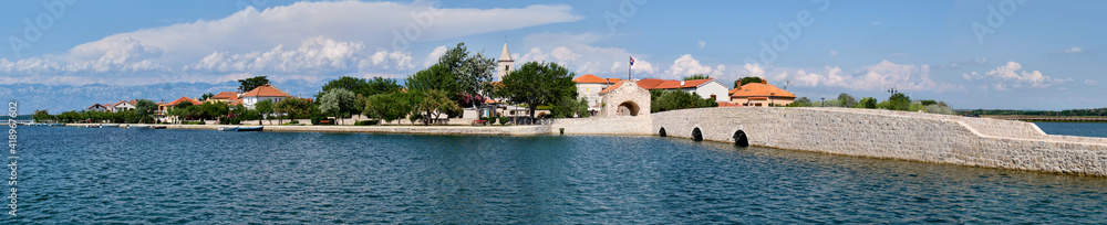 Panoramic image of Nin, historic medieval town in the Zadar County of Croatia. Panoramic banner image of bridge that leads to city center in a lagoon on the Adriatic Sea.