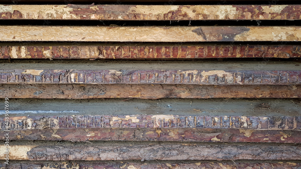 natural wooden boards stacked in a row on top of each other in a horizontal position as a background. decorative solution, shabby brown wooden planks with shabby bark. in the daytime, without people. natural wooden boards stacked in a row on top of each other in a horizontal position as a background. decorative solution, shabby brown wooden planks with shabby bark. in the daytime, without people.