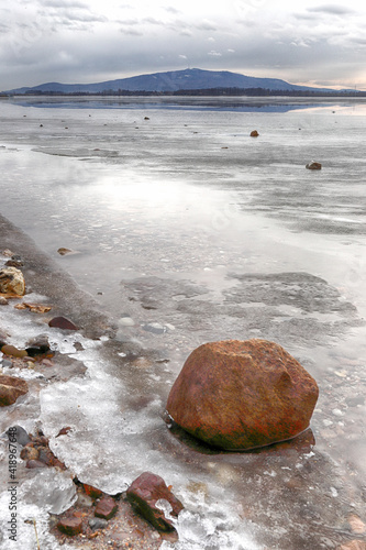 MIETKOW, POLAND - FEBRUARY 03, 2021: An ice-covered beach by the Mietkowski Lagoon, with the Sleza Mountain in the background. Mietkow near Wroclaw, Poland, Europe. photo