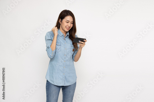 Cheerful Asian woman using smartphone and receiving good news from the message on mobile chat application over white background