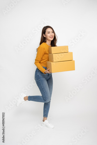 Happy Asian woman smiling and holding package parcel box isolated on white background, Delivery courier and shipping service concept, Full Length people composition © comzeal