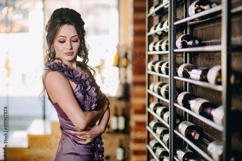 Closeup of cute girl looking down in front of shelves with wine and champagne bottles
