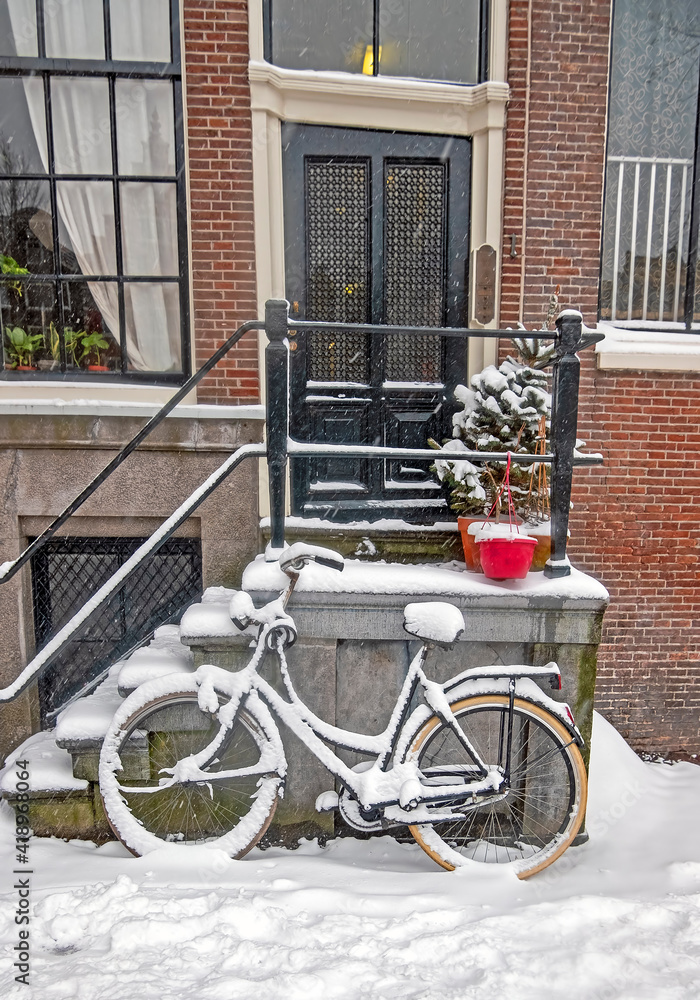 Snowy bike in front of a traditional house in Amsterdam the Netherlands