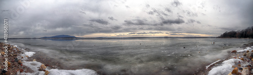 MIETKOW, POLAND - FEBRUARY 03, 2021: An ice-covered beach by the Mietkowski Lagoon, with the Sleza Mountain in the background. Mietkow near Wroclaw, Poland, Europe. photo