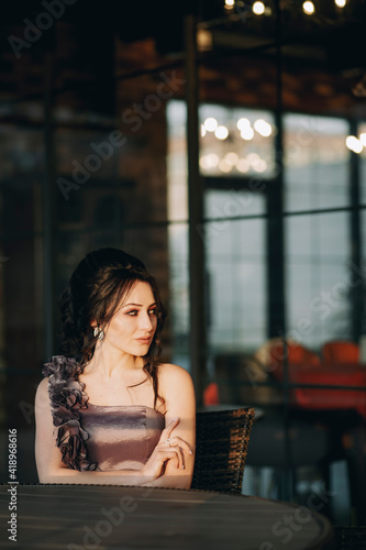 Obraz na płótnie Vertical shot of nice looking girl sitting in street cafe and enjoying her time in the evening w salonie