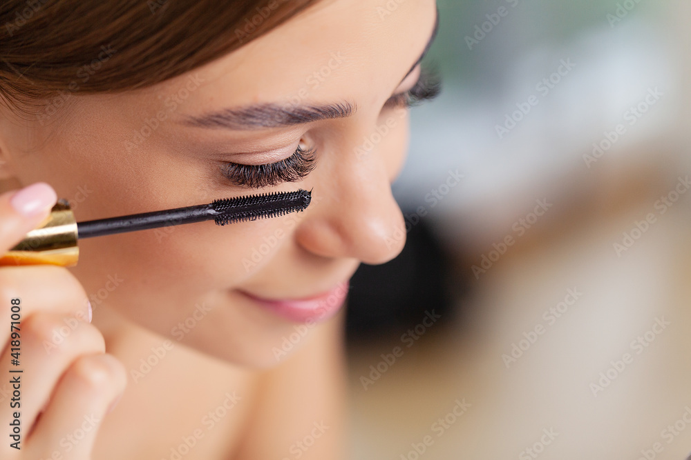 Young woman applying makeup on face at home Young woman applying makeup on face at home