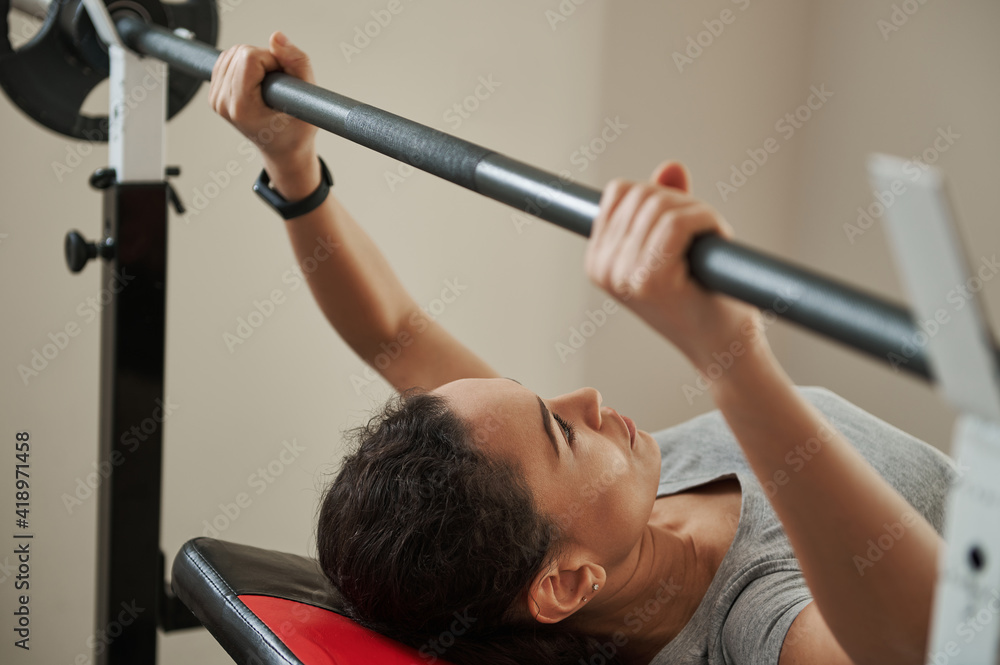 Young athlete woman concentrated on exercising bench press.