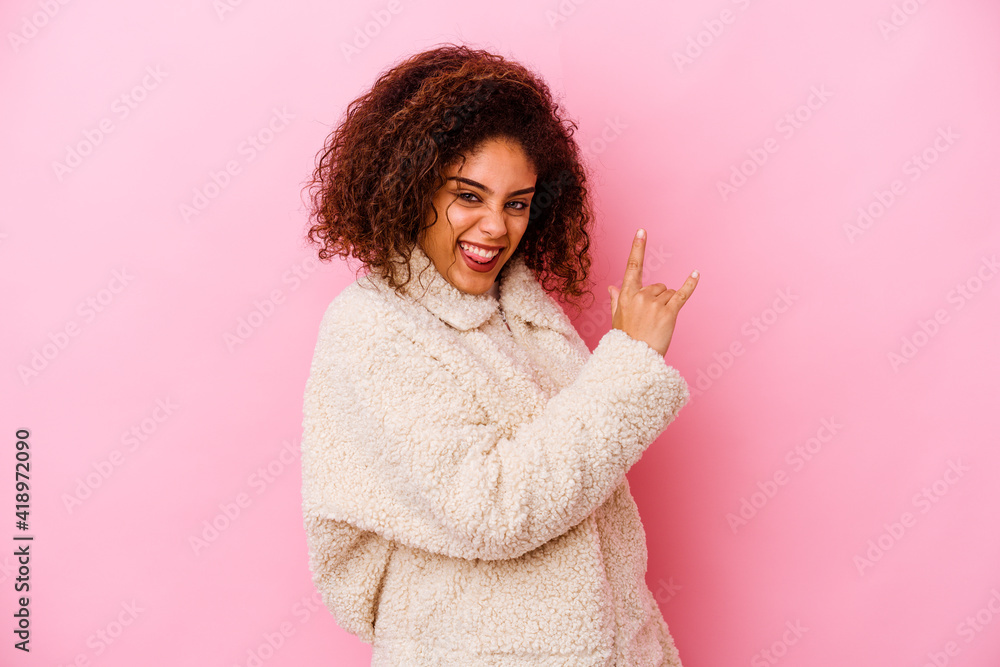 Young african american woman isolated on pink background showing rock gesture with fingers Young african american woman isolated on pink background showing rock gesture with fingers