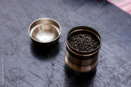 Tableau sur toile A steel jar full of black lintel or kali dal on a black wooden table