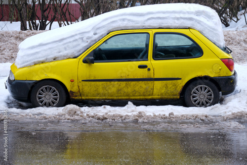 Car covered with layers of snow not cleaned in the winter parking lot