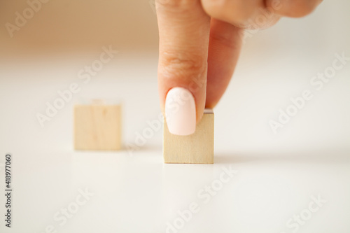 Woman hand putting and stacking blank wooden cubes on desk with copy space for input wording and infographic icon.