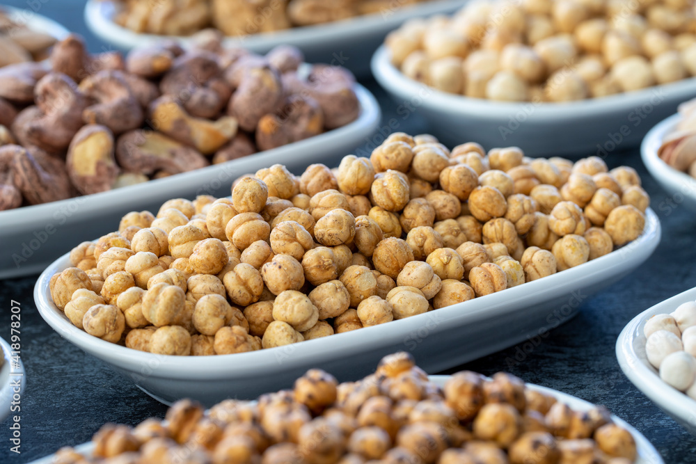 Roasted chickpeas in selective focus. Nuts on plate on a dark background. Walnut, Chickpeas, White Chickpeas, Dry mulberry, almond, cashew, pistachio. Types of nuts on the plate. Roasted chickpeas in selective focus. Nuts on plate on a dark background. Walnut, Chickpeas, White Chickpeas, Dry mulberry, almond, cashew, pistachio. Types of nuts on the plate.