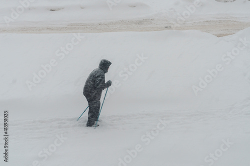 Old man walks in snowstorm practicing nordic poles walking in winter photo