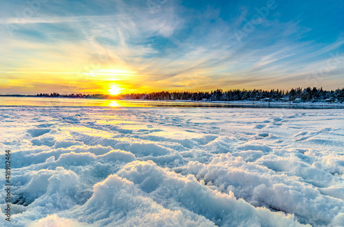 The panoroma of yellow horizon and sunset in snow-covered beach during winter