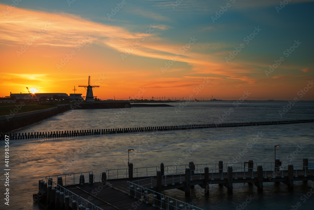 Sunrise at the harbor in Vlissingen, the Netherlands. You can see the sea, breakwaters and beautiful colorful sky.