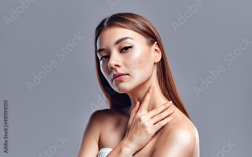 Beautiful young woman with clean perfect skin. Portrait of beauty model with natural nude makeup. Spa  skin care and wellness. Close up  gray background  copyspace.