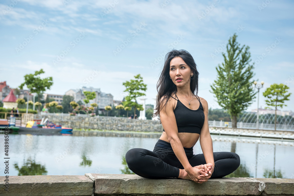 Young slim woman in sportswear practicing yoga near lake, nature. Healthy lifestyle