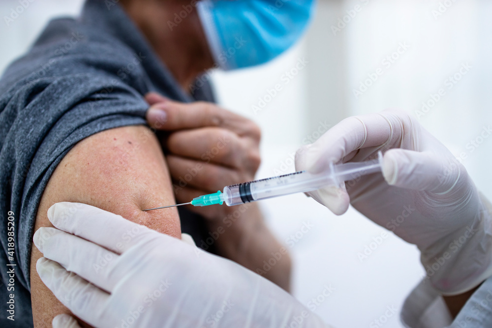 Close up view of an old man getting vaccine shot in his arm during corona virus pandemic. Close up view of an old man getting vaccine shot in his arm during corona virus pandemic.