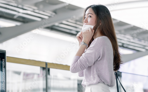 Woman wearing face mask and waiting for a train while standing on railway station