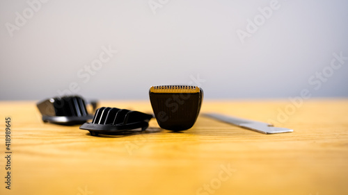 side view, focus on the blade of a typewriter, a set of hairdresser, a typewriter, a comb and nozzles, lie on a wooden table