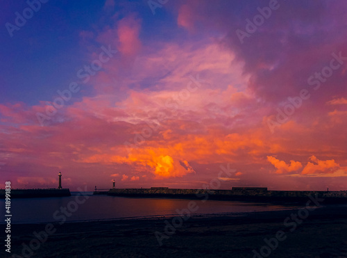The lighthouses and piers at Whitby on the North Yorkshire Coast, under a sky reflecting the sunset.