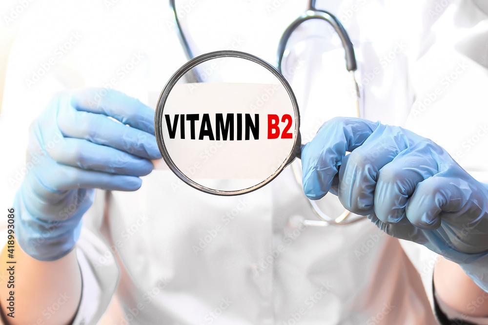 The doctor's blue - gloved hands show the word VITAMIN B2 - . a gloved hand on a white background. Medical concept. the medicine The doctor's blue - gloved hands show the word VITAMIN B2 - . a gloved hand on a white background. Medical concept. the medicine
