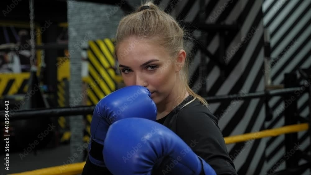 Portrait of a young focused woman during boxing training, she practices punches in front of the camera. Portrait of a young focused woman during boxing training, she practices punches in front of the camera.