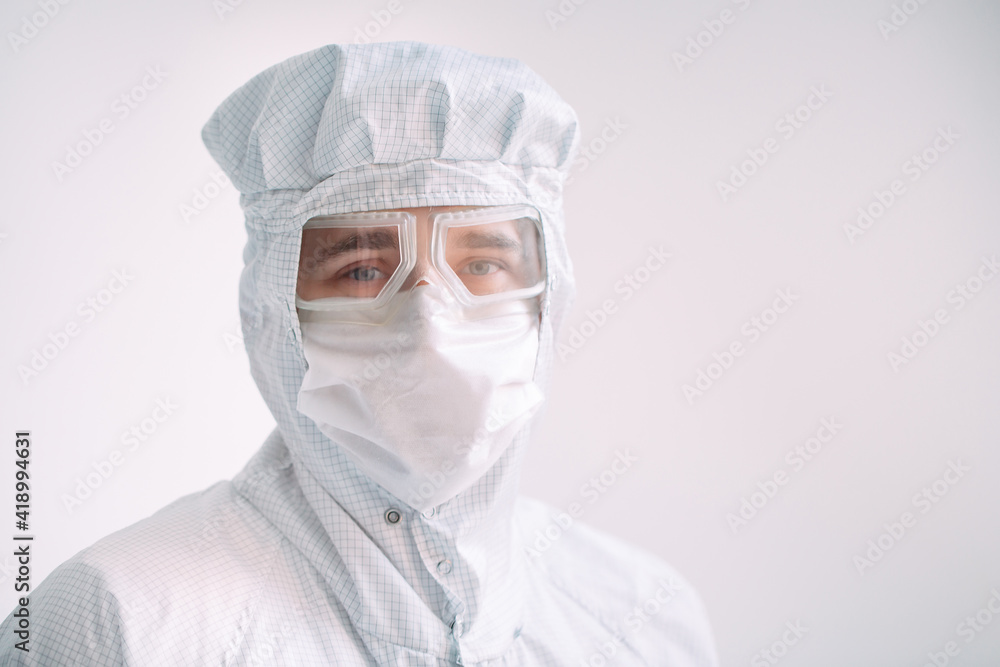 Portrait of a male doctor of European appearance in a medical mask, protective glasses and chemical suit. Portrait of a male doctor of European appearance in a medical mask, protective glasses and chemical suit.