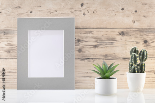 Modèle de cadre photo blanc avec espace vide pour logos, inscription publicitaire. Cadre en mode portrait sur un espace de travail avec des plantes vertes. Ambiance zen. © ODIN Daniel