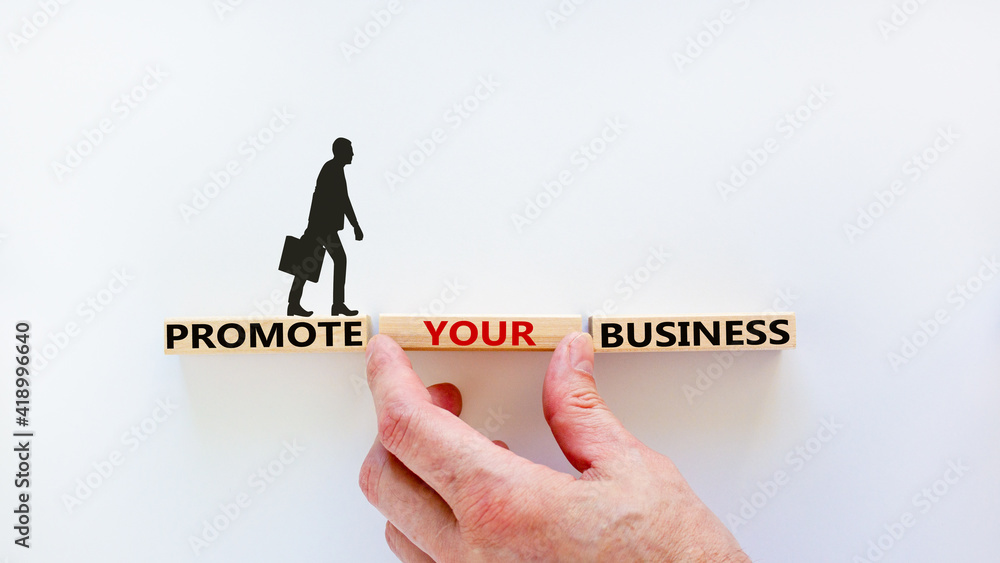 Promote your business symbol. Wooden blocks with words 'Promote your business' on beautiful white background. Businessman hand. Businessman icon. Promote your business concept. Copy space. Promote your business symbol. Wooden blocks with words 'Promote your business' on beautiful white background. Businessman hand. Businessman icon. Promote your business concept. Copy space.
