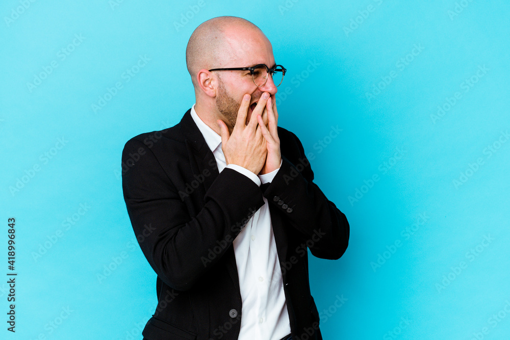 Young business caucasian bald man isolated on blue background laughing about something, covering mouth with hands. Young business caucasian bald man isolated on blue background laughing about something, covering mouth with hands.