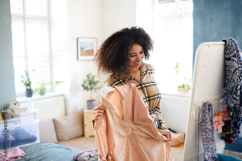 Young woman sorting wardrobe indoors at home, charity donation concept.