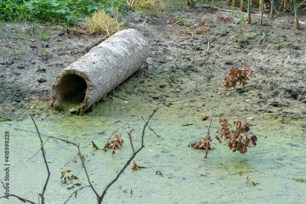 Obraz premium dirty water in the river. Environmental pollution. Construction waste. The asbestos pipe lies on the bank of the river. The world problem of drinking water pollution.