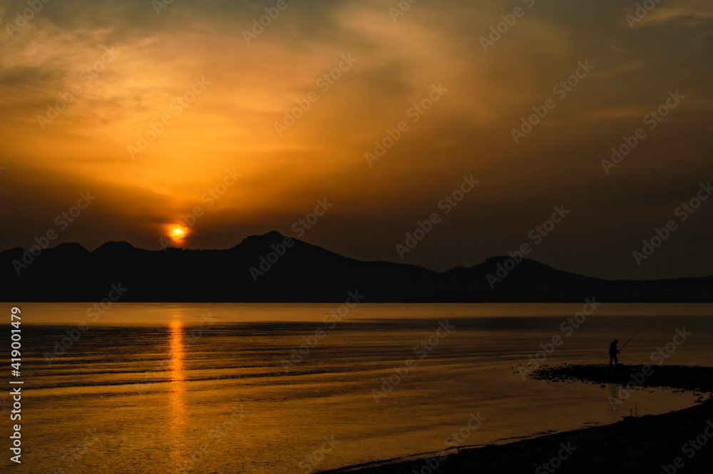 Obraz premium Sunrise yellow orange sky with man fishing 