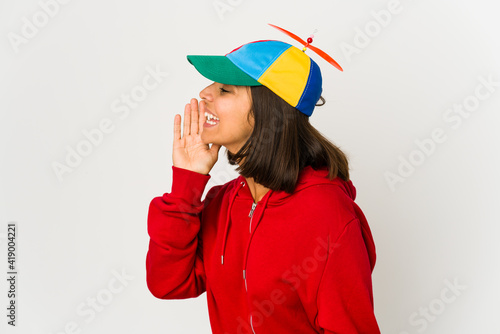 Young hispanic woman wearing a cap with propeller isolated shouting and holding palm near opened mouth.