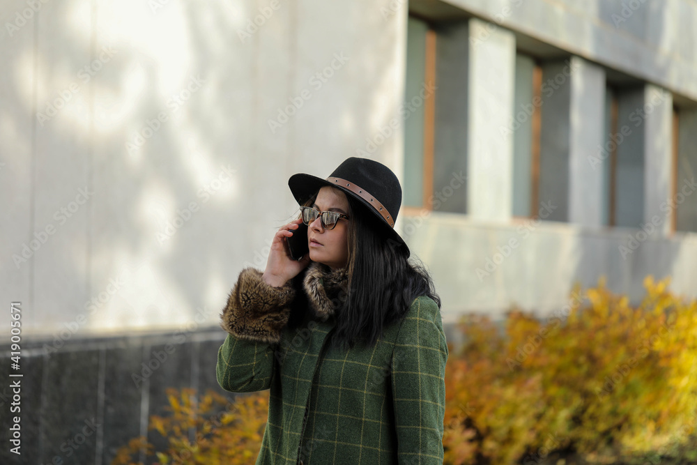 Woman talking on mobile phone . Beautiful girl talking on mobile phone in sunny spring day .