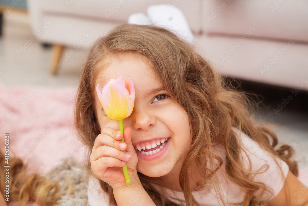 A little girl lies on the floor and smiles holding a tulip presented to her A little girl lies on the floor and smiles holding a tulip presented to her