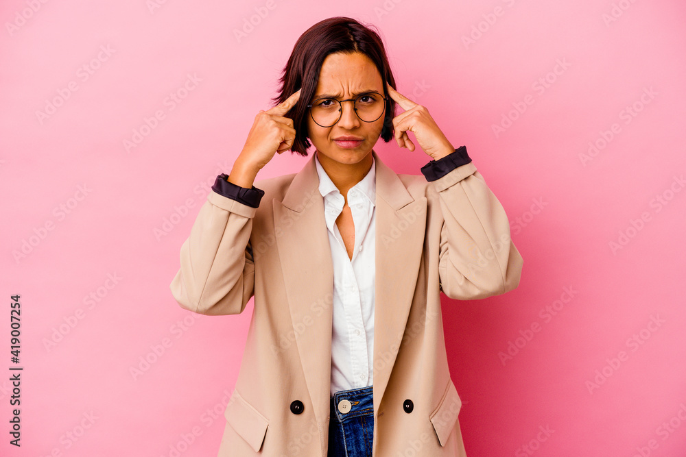 Young business mixed race woman isolated on pink background focused on a task, keeping forefingers pointing head. Young business mixed race woman isolated on pink background focused on a task, keeping forefingers pointing head.