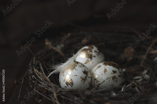 easter background with golden eggs in a nest on a dark wooden background close up, copy space
