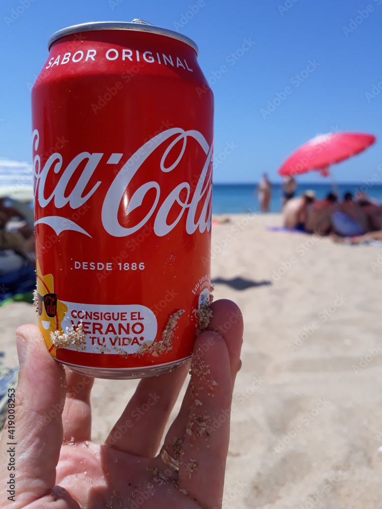 Hand Holding A Can Of Coca-Cola On The Beach. Summer Concept Stock 