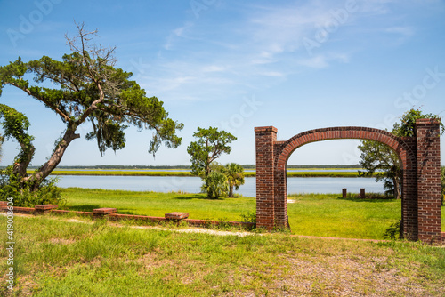 Remains of brick archway with view of Medway River at Sunbury Georgia on sunny day with bright blue sky
